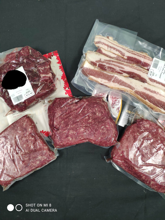 Assorted packages of dry aged pasture raised beef in stew meat, prime grind and ground beef, with a side of thick cut bacon from Southern Alberta.