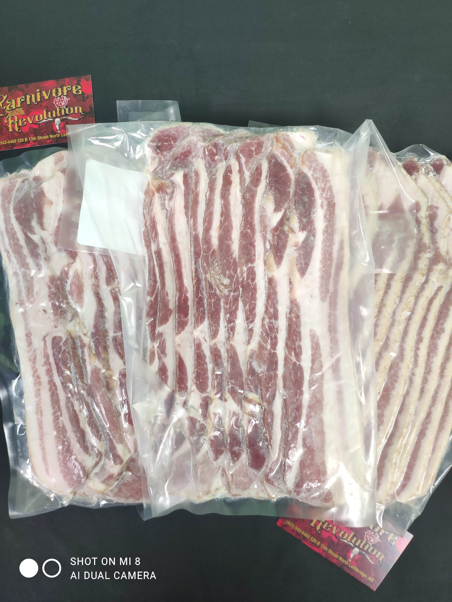 Multiple packages of thick cut bacon, wrapped and placed side by side.